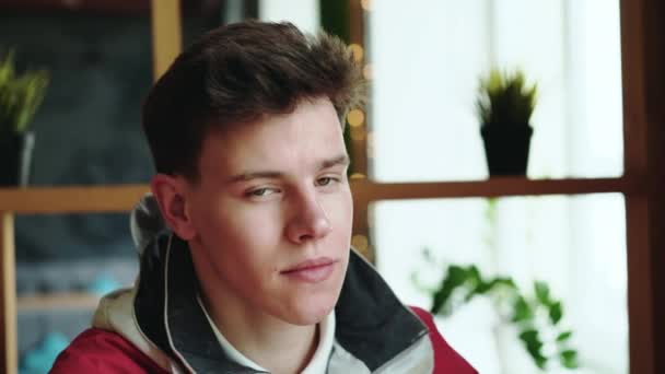 Портрет молодого человека сидит в кафе и смотрит в камеру. 4K — стоковое видео