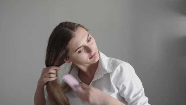 Όμορφη γυναίκα χτενίζει τα μαλλιά στο φως δωμάτιο — Αρχείο Βίντεο