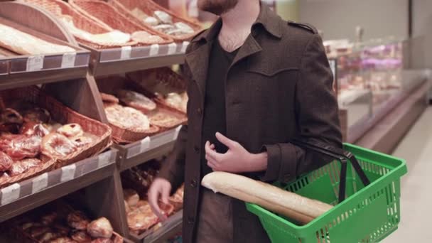 Mannen lägger limpor i korgen och ler mot kameran i snabbköpet — Stockvideo