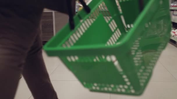 Nízký pohled na nepoznatelnou osobu s košíkem v ruce procházky v supermarketu — Stock video