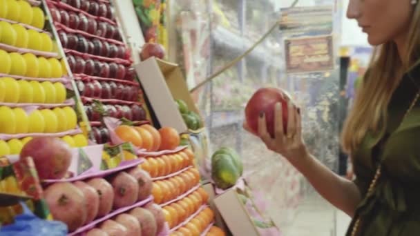 Молодая женщина выбирает гранат в фруктовом магазине. 4K — стоковое видео