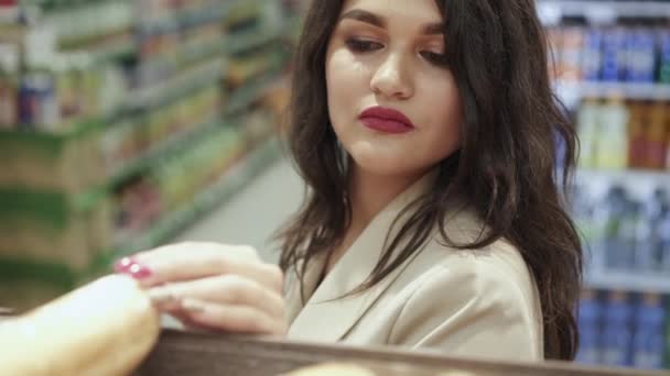 Porträt einer glamourösen Dame, die sich im Supermarkt für ein Baguette entscheidet — Stockvideo