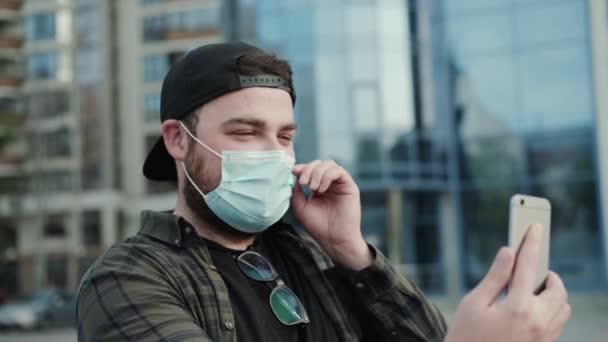 Uomo in abiti casual in maschera medica chatta online sulla fotocamera degli smartphone — Video Stock
