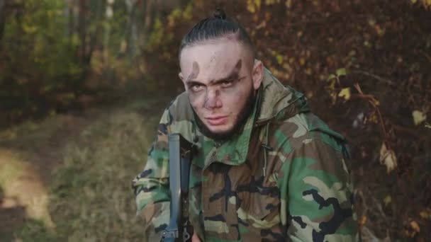 Portrait of hunter with soot strips on face aims gun at an object in the forest — Stock Video