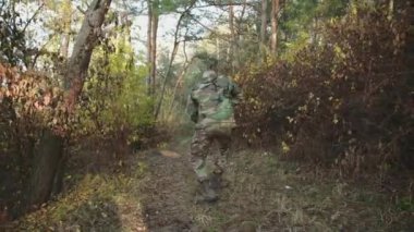 Asker, ormanda tüfekle farklı yönlere nişan alıyor.