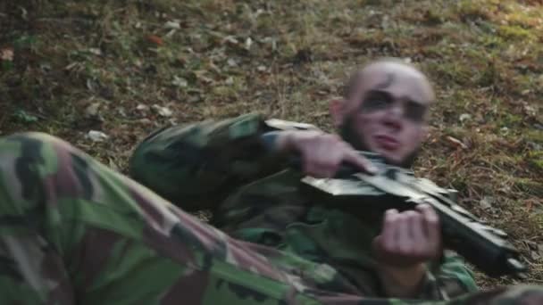 Soldado en uniforme de camuflaje se arrastra por la espalda con un rifle en el camino — Vídeos de Stock