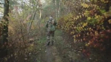 Ormanda elinde tüfekle koşan ve etrafa bakınan askerin arkası.