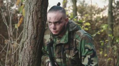 Asker, düşmanın ağaçtan gelen gürültüyü duyduğunda lazer tüfeği görüşüne bakar.