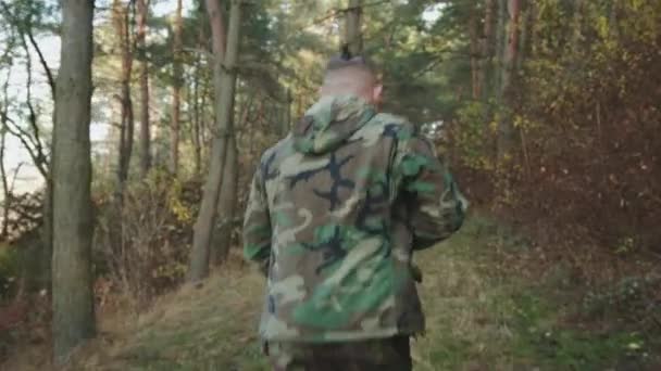 Soldado en camuflaje trotando con un rifle en el bosque y mirando a su alrededor para apuntar — Vídeos de Stock