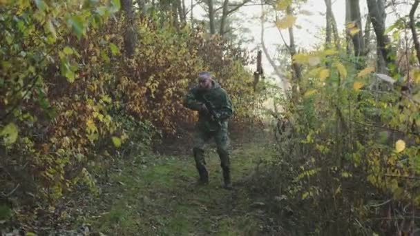 Soldier looking for a trace of the enemy with a rifle in a forest — Stock Video