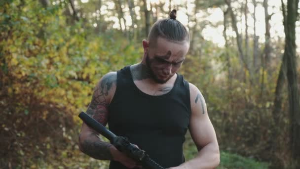 Brutal athlete with soot strips on face infects a rifle and aims at an object — Stock Video