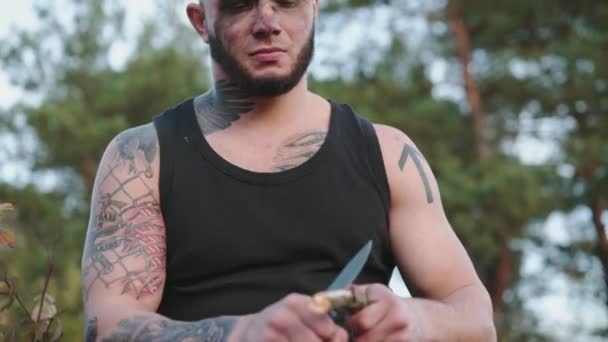 Mann schärft Holzspäne mit Messer auf die Natur und wirft sie runter — Stockvideo
