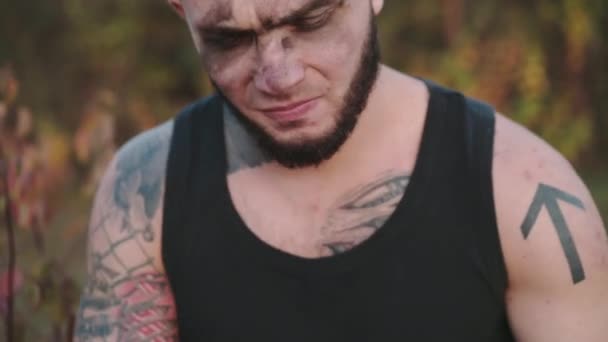 Brutal man with soot on face sharpening shavings and looking on it on nature — Stock Video