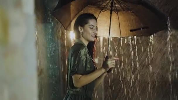 Morena apaixonada posando com guarda-chuva sob chuva forte noite — Vídeo de Stock
