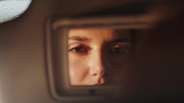 Reflexão da mulher no espelho frontal do carro, que abre os olhos e olha — Vídeo de Stock