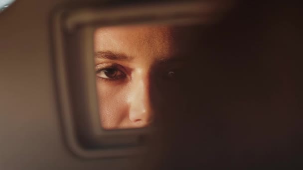 Reflexão da mulher no espelho retrovisor do carro, que aplica brilho labial e sorrindo — Vídeo de Stock