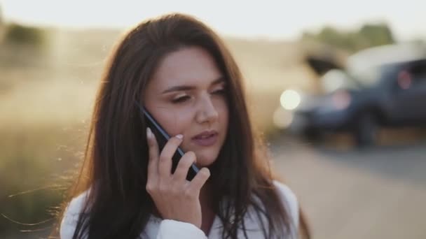 Alleen dame drinkt een kopje thee en praat emotioneel over de telefoon bij een kapotte auto — Stockvideo