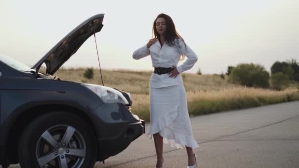 Vista de la mujer nerviosa desconcertante no estar de pie y mira bajo el capó fuera de la ciudad — Vídeos de Stock