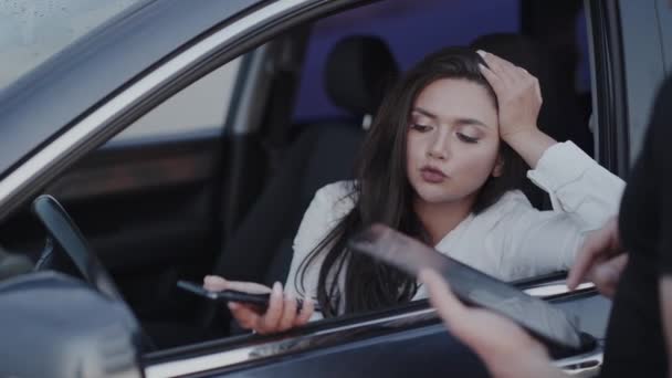 Morena bonita no carro conversando com o oficial, eles usando gadgets e se alegrando — Vídeo de Stock