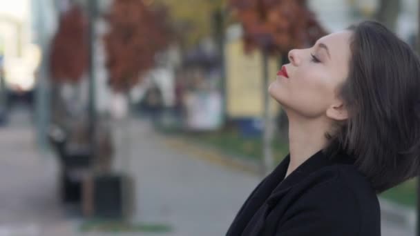 Elegáns hölgy bólogat a fejét frizurával, és félrenéz az utcán — Stock videók