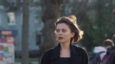 Zarif bayanın portresi, güneşli sokaklar arasındaki rüzgardan saç stilini düzeltir.