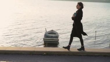 Bir bardak içkisi olan bir kadın rüzgarlı bir gecede sınırda yürüyor.