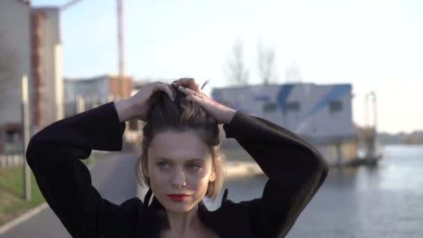 Belle fille pose avec ses cheveux à la caméra au lac de la ville