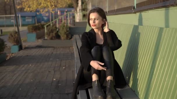 Playful woman relaxing on street bench and nodding her head — Stock Video