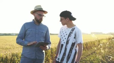 İki çiftçi gün batımında tablet kullanarak kendi aralarında konuşuyor.