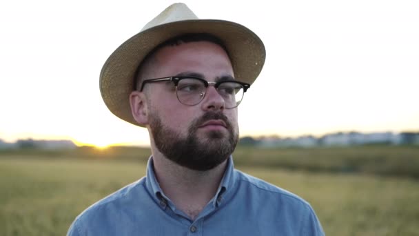 Şapkalı özgüvenli bir adamın yakın plan portresi tarlaların arasında duruyor. — Stok video