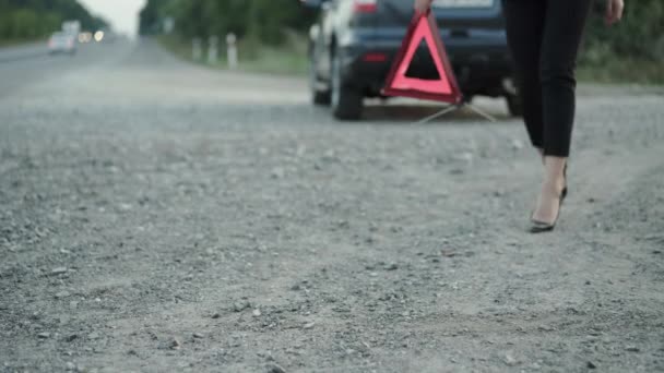 Vista baja de la mujer con el automóvil roto, la instalación de señal de triángulo rojo en la carretera — Vídeos de Stock