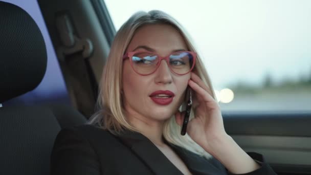 Blonde talks with smile on the smartphone when sits in the car on front seat — Stock Video