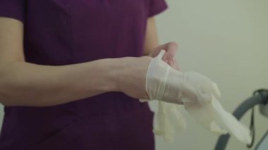 Tanımlanamayan kadın kozmetolog ameliyattan önce tek kullanımlık eldiven takıyor.