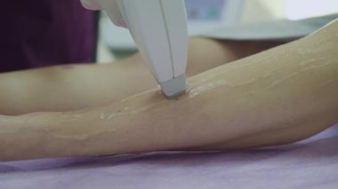 Güzellik uzmanının eli kanepede ince kadın bacakları sarkıtıyor.