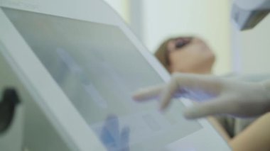 Güzellik salonundaki cihazın ekranına yazı yazan bir güzellik uzmanının eli.