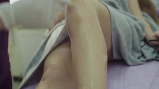 Применение геля с лопаткой на ногах клиента перед лазерной эпиляцией — стоковое видео