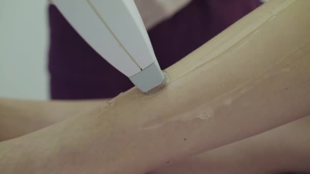 Κλείσιμο αφαίρεσης τρίχας laser σε γυναικεία λεπτά πόδια ξαπλωμένα στον καναπέ στο δωμάτιο θεραπείας — Αρχείο Βίντεο