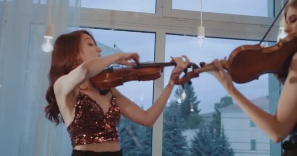 Dueto de músicos alegres do sexo feminino tocando violinos na janela interior — Vídeo de Stock