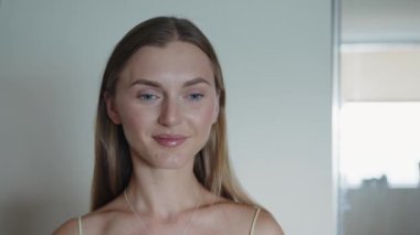 Makyaj fırçası, fırçayla makyaj tozu süren gülümseyen bir kadının yüzü. Stüdyodaki gri arka planda mutlu ve izole. Portre, kozmetik ürün ve modelin tozu, cilt temeli ve yüz güzelliği..