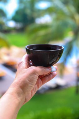 Bulanık arka planda elinde Seylan çayı olan hindistan cevizi kupası