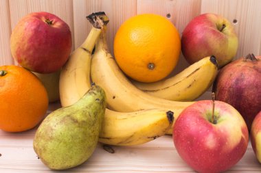 Çeşitli meyve elma, muz, portakal, nar doğal ahşap zemin üzerinde. Sağlıklı gıda