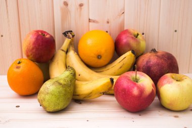 Çeşitli meyve elma, muz, portakal, nar doğal ahşap zemin üzerinde. Sağlıklı gıda