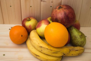 Çeşitli meyve elma, muz, portakal, nar doğal ahşap zemin üzerinde. Sağlıklı gıda