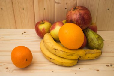 Çeşitli meyve elma, muz, portakal, nar doğal ahşap zemin üzerinde. Sağlıklı gıda