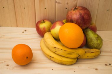 Çeşitli meyve elma, muz, portakal, nar doğal ahşap zemin üzerinde. Sağlıklı gıda