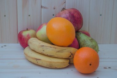 Çeşitli meyve elma, muz, portakal, nar doğal ahşap zemin üzerinde. Sağlıklı gıda