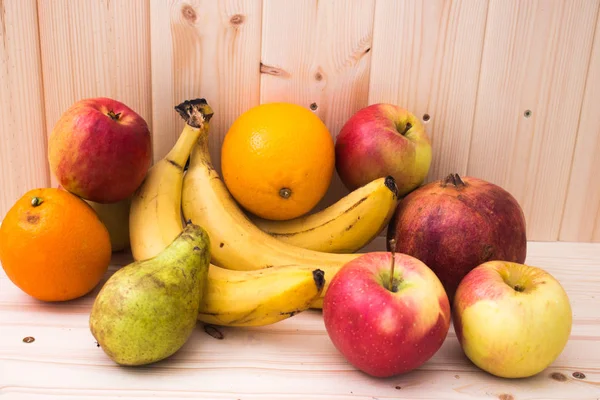 Çeşitli meyve elma, muz, portakal, nar doğal ahşap zemin üzerinde. Sağlıklı gıda