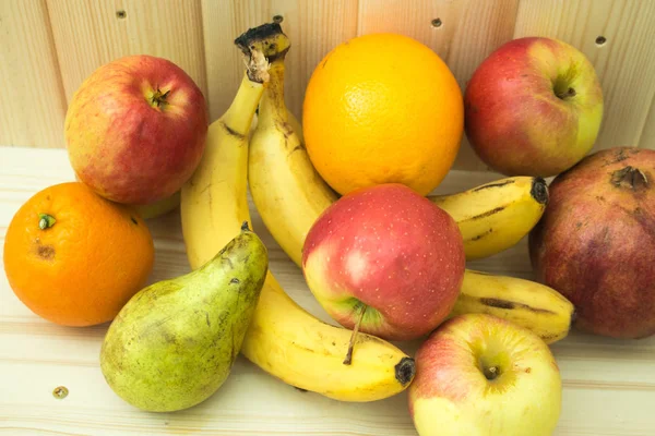 Çeşitli meyve elma, muz, portakal, nar doğal ahşap zemin üzerinde. Sağlıklı gıda