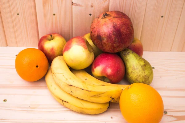 Çeşitli meyve elma, muz, portakal, nar doğal ahşap zemin üzerinde. Sağlıklı gıda