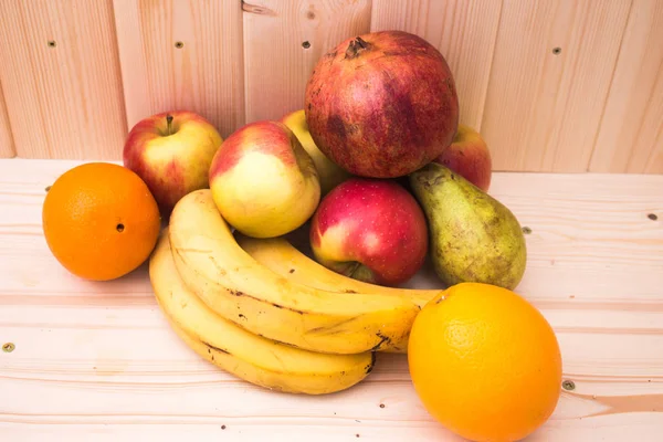Çeşitli meyve elma, muz, portakal, nar doğal ahşap zemin üzerinde. Sağlıklı gıda